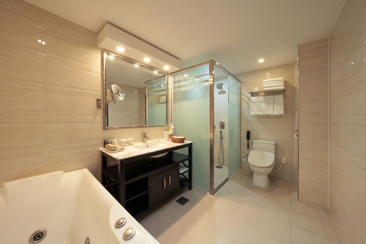 Une salle de bain moderne avec une douche à parois de verre, un grand miroir, une baignoire et des toilettes.
