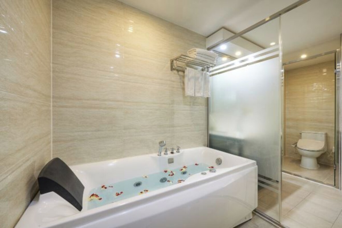 A modern bathroom with a freestanding bathtub, a glass shower enclosure, and a toilet visible through the glass.