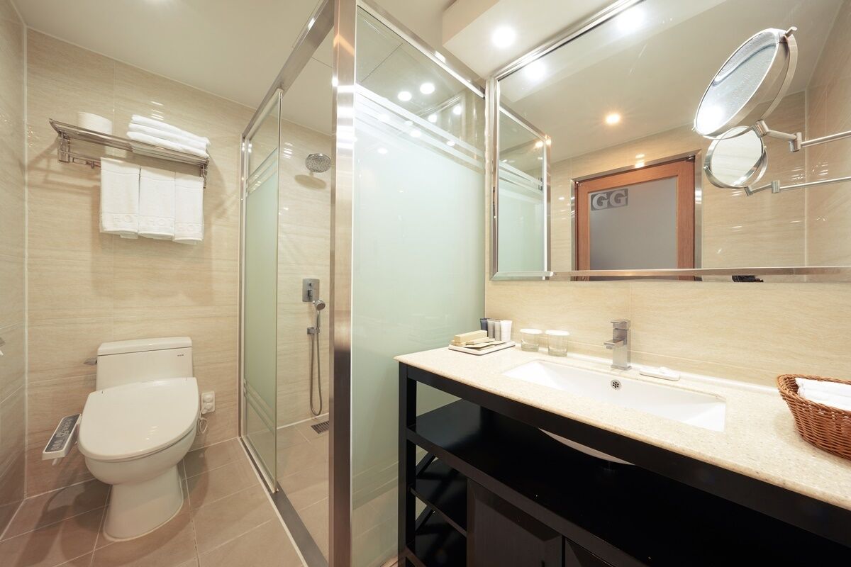 A modern bathroom with a glass shower enclosure, a toilet, a sink with a mirror, and a towel rack.
