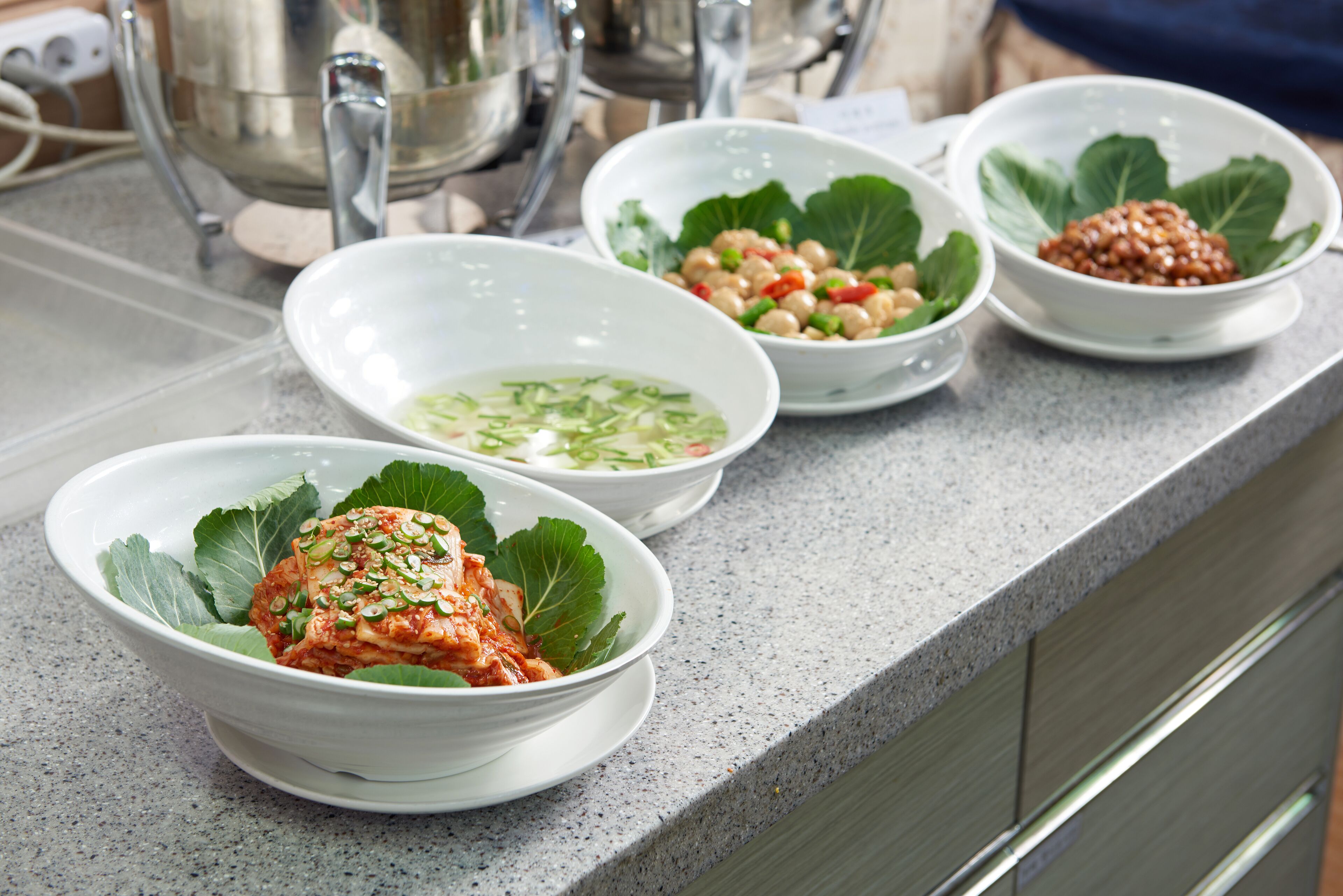 A kitchen counter with three bowls of food, each with different ingredients and garnishes.