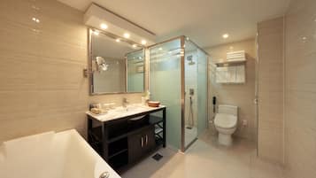 A modern bathroom with a bathtub, vanity, glass shower enclosure, and a toilet.