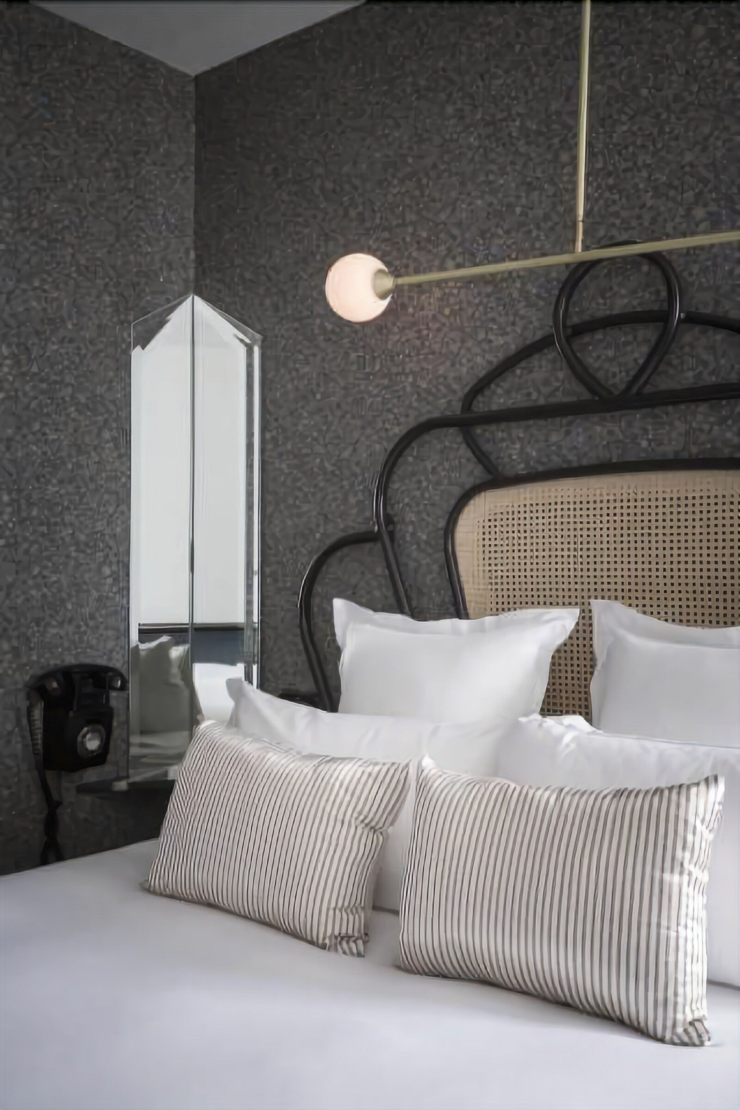 Habitació d'hotel moderna amb un llit gran, un telèfon al costat del llit i un mirall a la paret.
