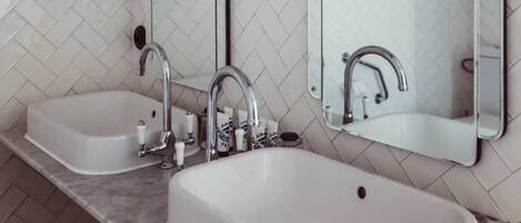 Ein Badezimmer mit zwei Waschbecken, einem Spiegel und einer Wand mit Fischgrätmuster.