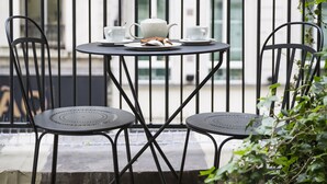 A balcony with a table and chairs, surrounded by potted plants. - Hotel Panache (Paris)
