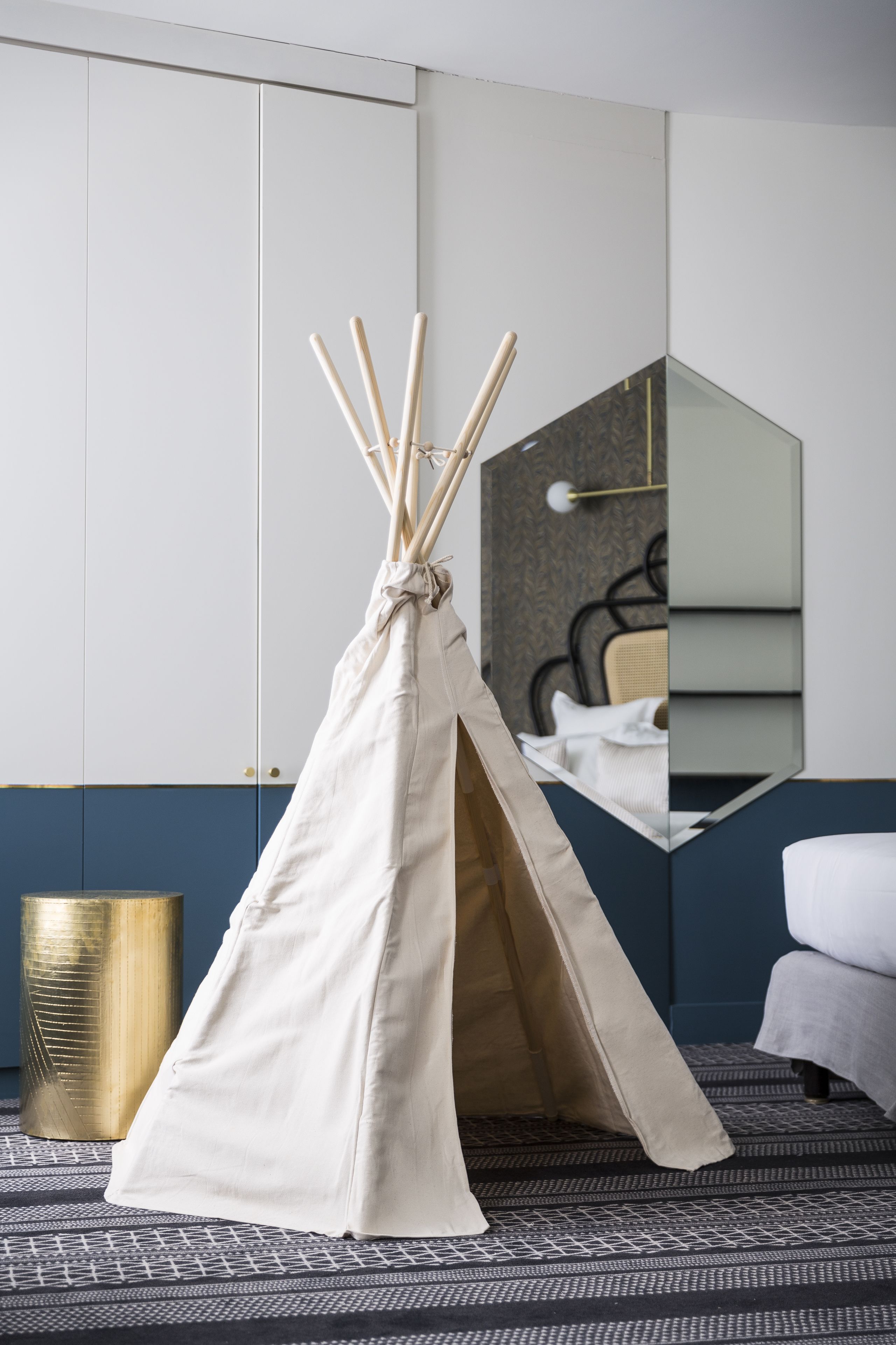 Una habitación con una estructura tipo tipi blanca, una cama, un espejo y una alfombra estampada.