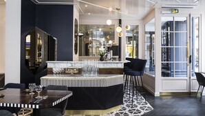 A modern bar area with a marble countertop, bar stools, and a patterned rug. - Hotel Panache (Paris)