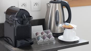 A kitchen counter with a coffee maker, a kettle, and a muffin display.
