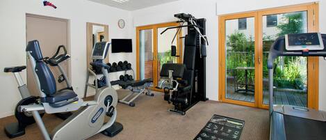 Un gimnasio con equipo de cardio, máquinas de pesas y mancuernas.