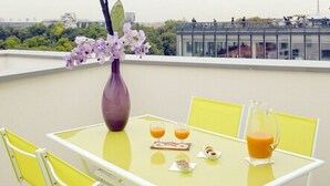 Une table avec des chaises jaunes et un vase de fleurs sur un balcon.