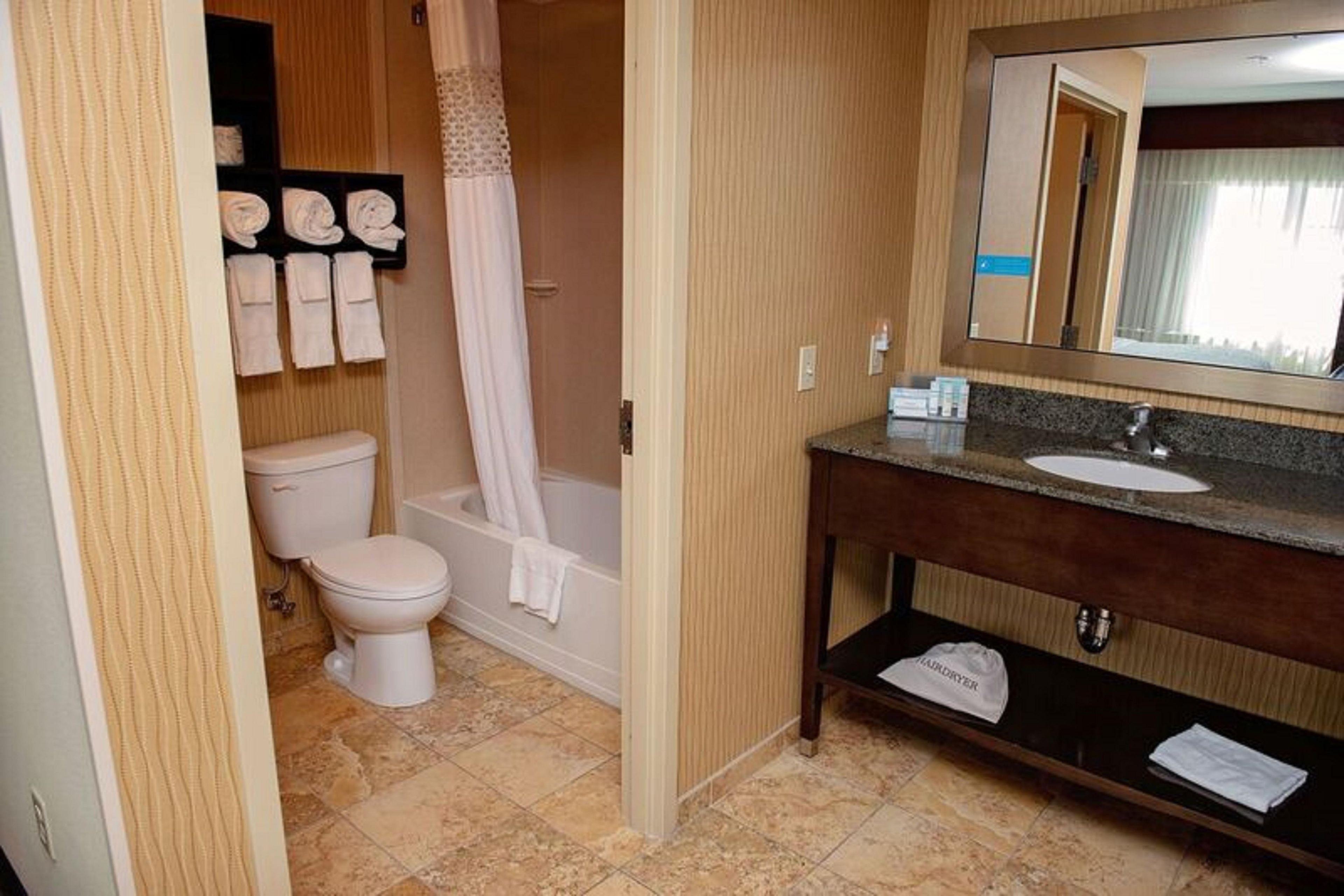 Un baño con inodoro, bañera y tocador con espejo.