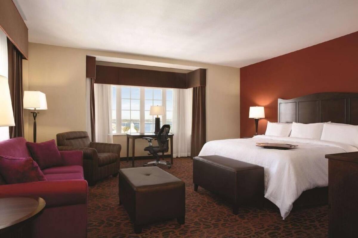 A hotel room with a bed, a desk, a chair, and a sofa.