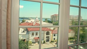 A view through a window of a building with a red-tiled roof, a white facade, and a clear blue sky.