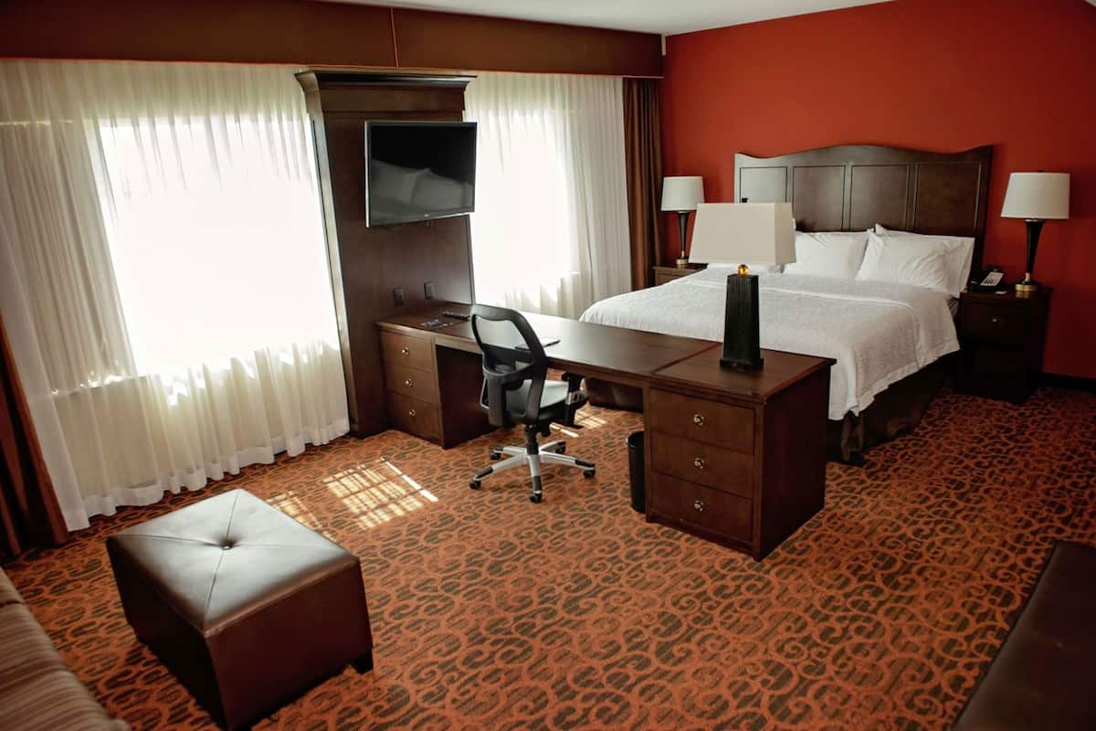 A hotel room with a bed, desk, chair, and a television.