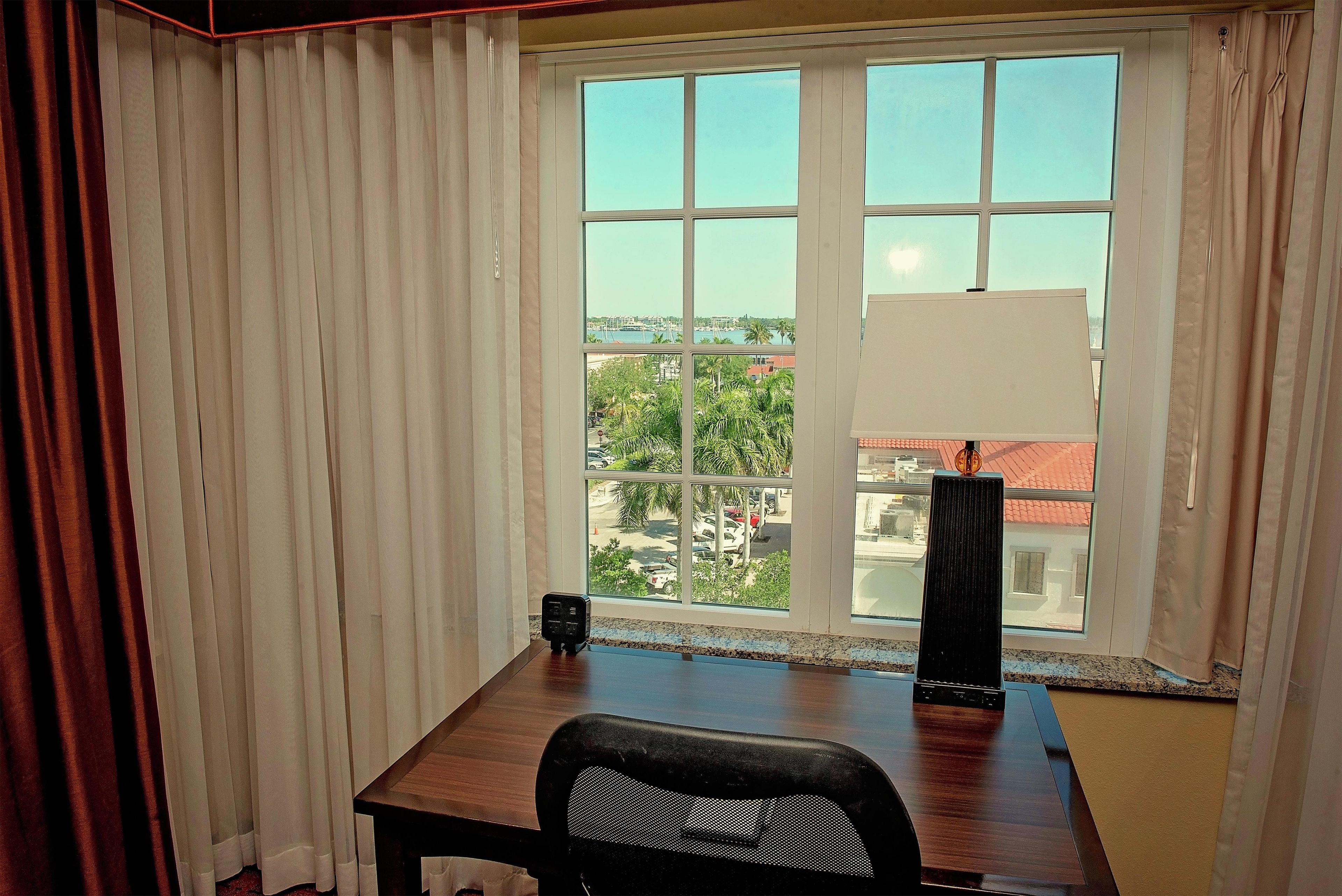 A room with a large window, a desk, and a chair.
