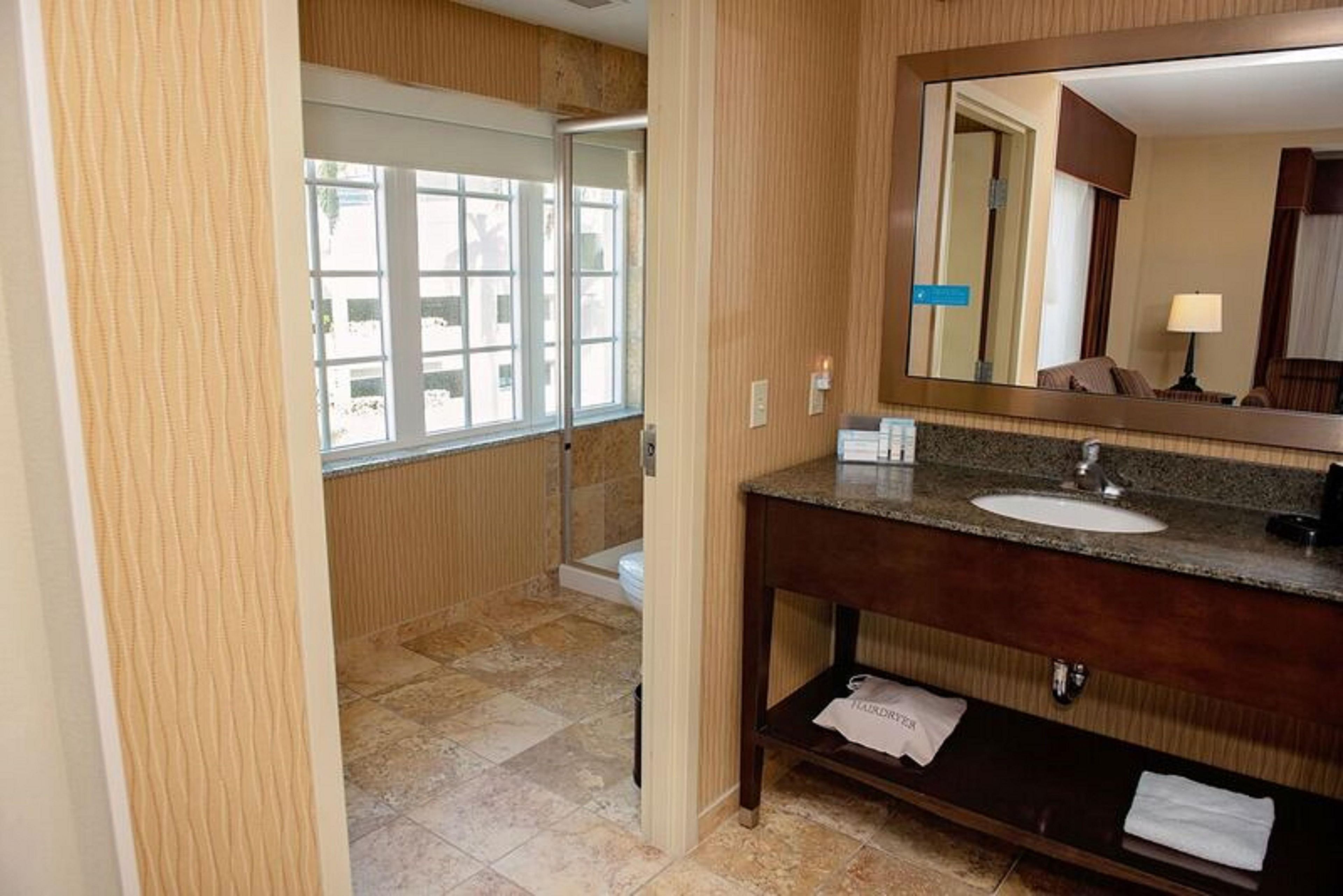 Een hotelbadkamer met een grote spiegel, een wastafel en een douche.