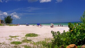 A beach with people, umbrellas, and a clear sky.