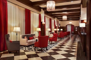 A hotel lobby with a checkered floor, red and white curtains, and multiple seating areas with lamps. - Hampton Inn & Suites Bradenton Downtown Historic District (Bradenton)