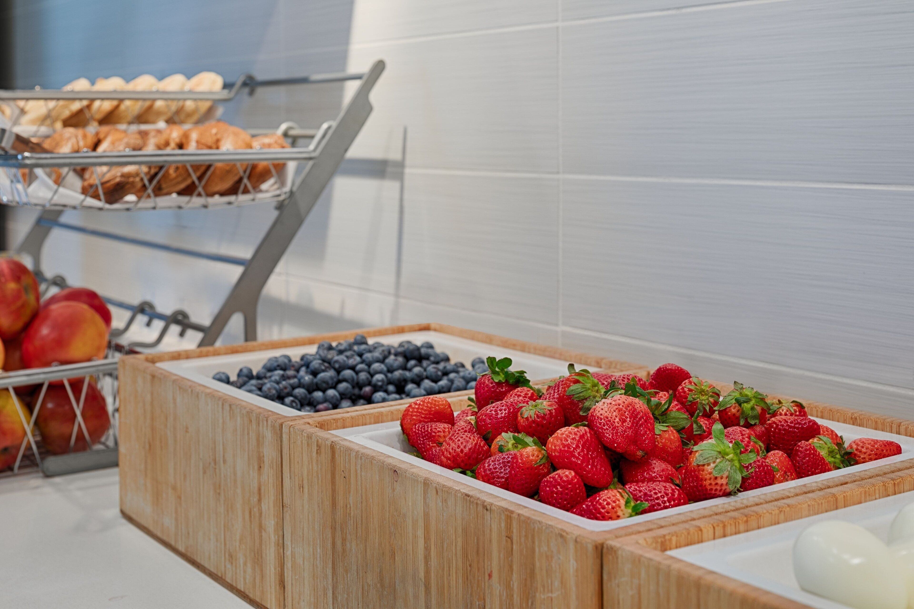 A breakfast buffet with wooden fruit and pastry containers.