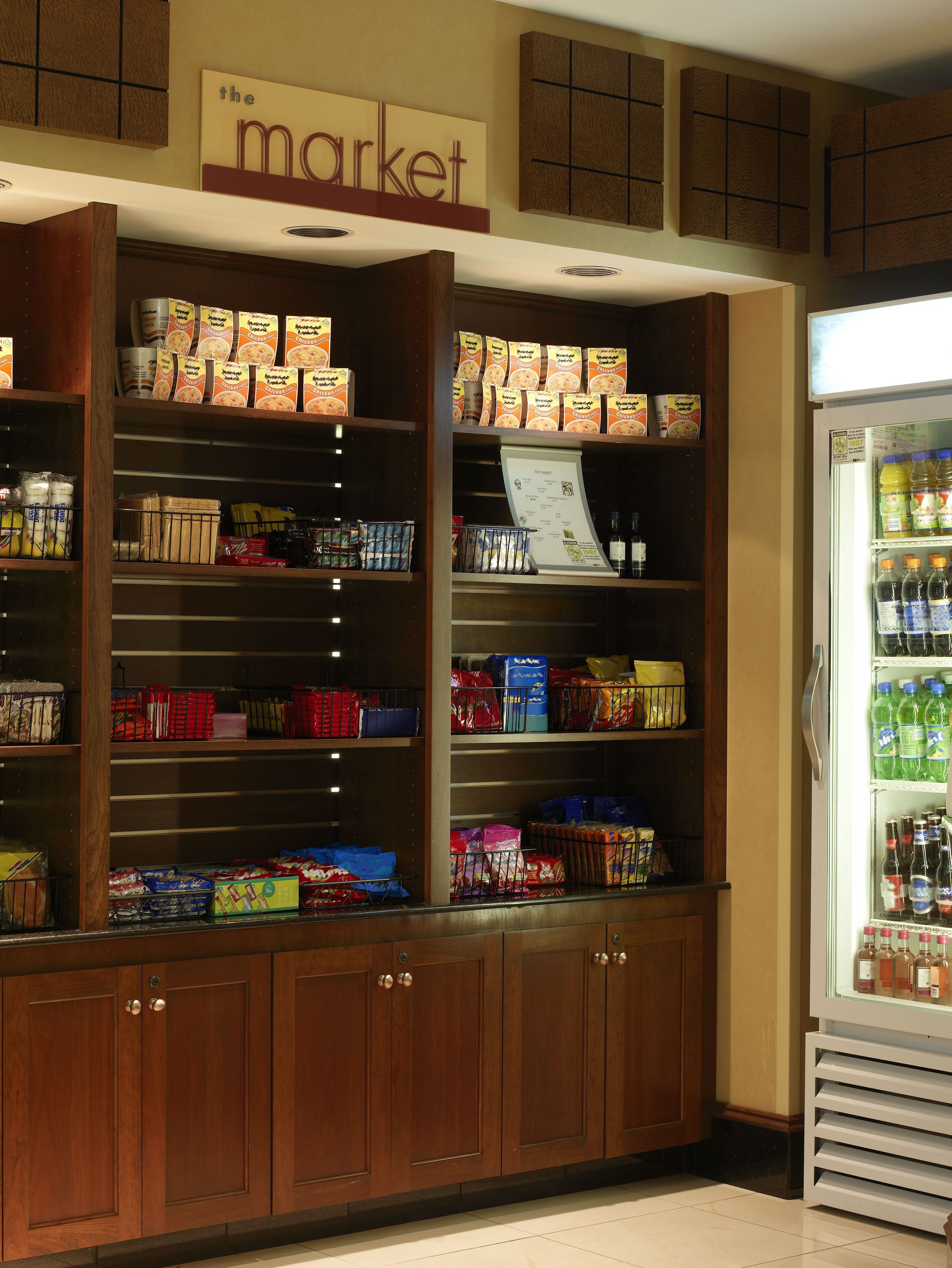 Een supermarktinrichting met houten schappen vol diverse etenswaren en een koelgedeelte rechts.