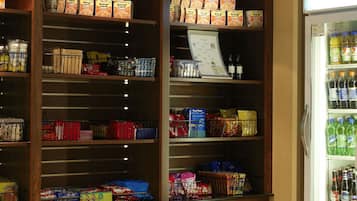 Een supermarktinrichting met houten schappen vol diverse etenswaren en een koelgedeelte rechts.