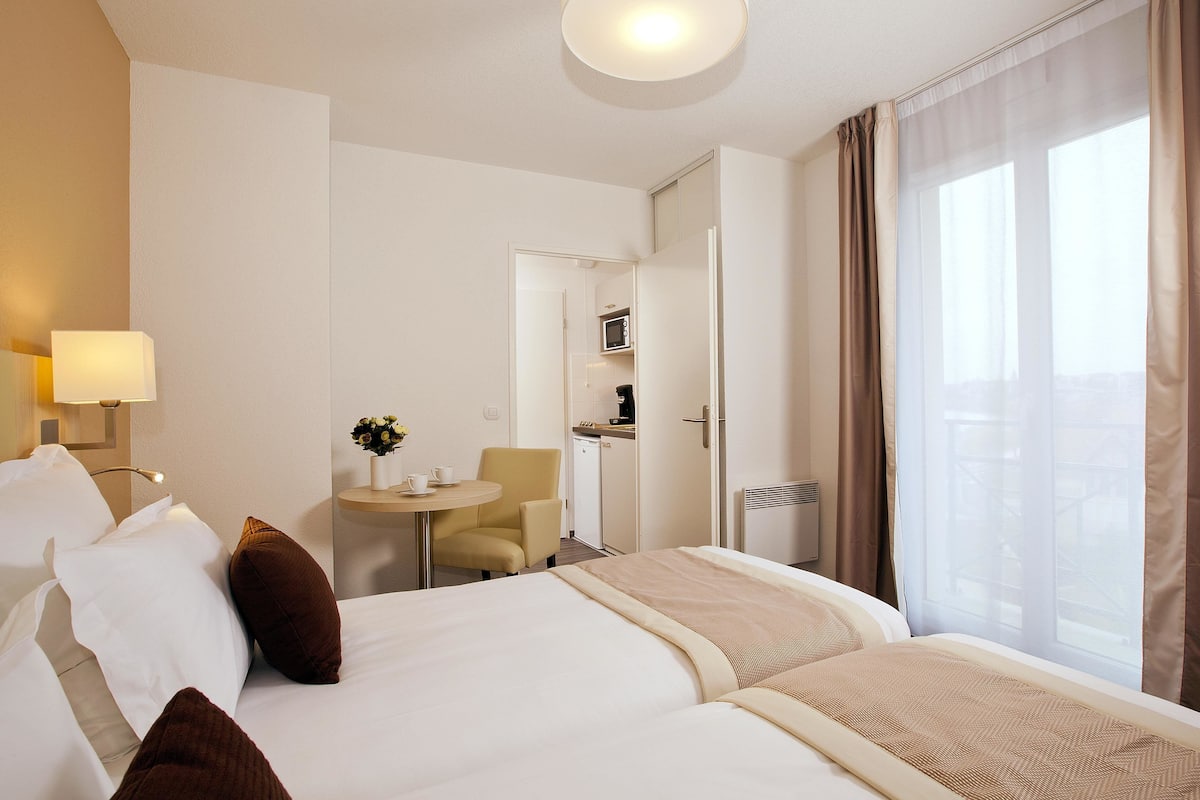 Een hotelkamer met een bed, een klein tafeltje met stoel, een magnetron en uitzicht op de omgeving.