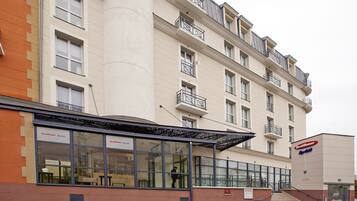 Un hôtel à plusieurs étages doté d’une façade moderne, de grandes fenêtres et d’un espace d’entrée abrité.