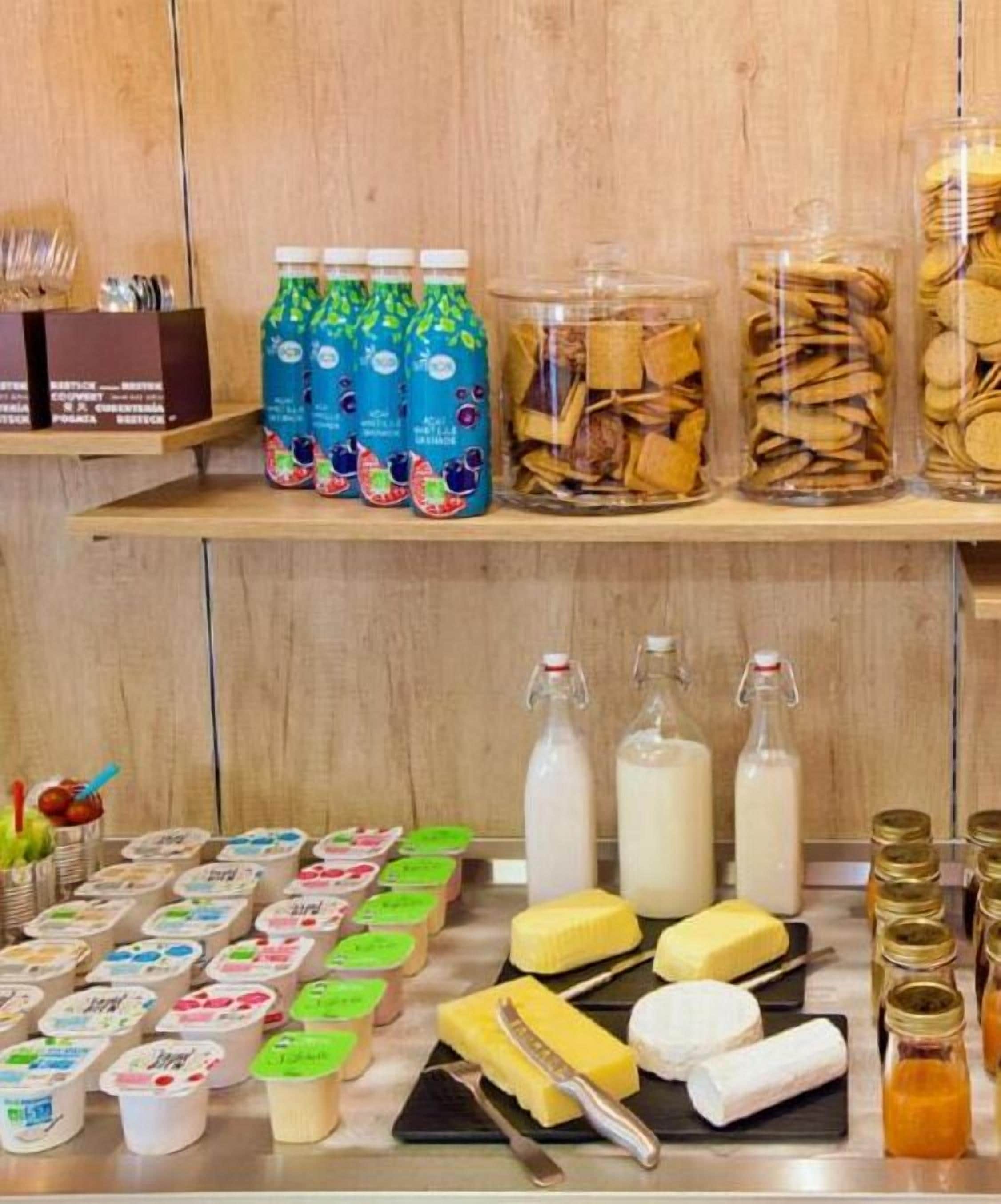 A kitchen counter with various food items and condiments, including jars of pickles, bottles of milk, and containers of yogurt.