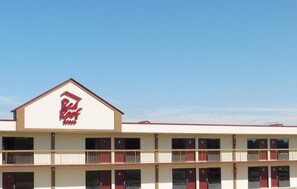 Un edificio de dos pisos con techo rojo y un letrero rojo y blanco que dice 'Red Roof Inn'.