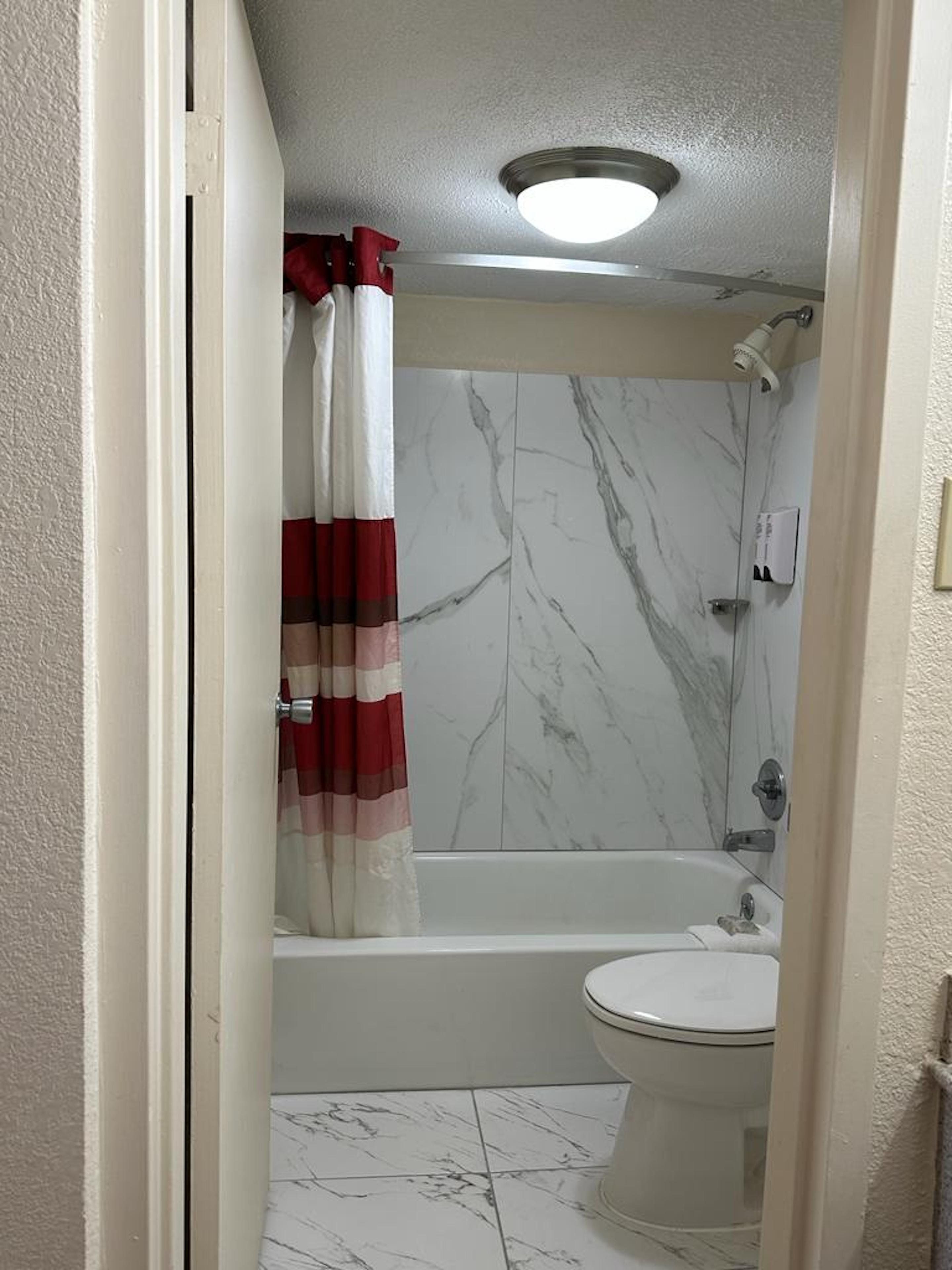 A bathroom with a bathtub, toilet, and marble walls.