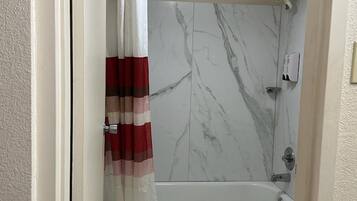 A bathroom with a bathtub, toilet, and marble walls.
