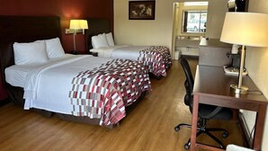 Una habitación de hotel con dos camas, un escritorio, una silla, una lámpara, un cuadro y una ventana.