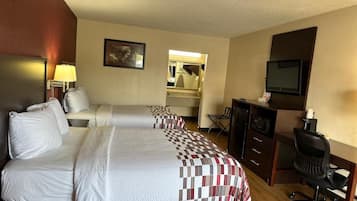 A hotel room with two beds, a desk, a chair, a television, and a mirror.