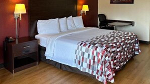 A hotel room with a large bed, two bedside lamps, a small desk, and a chair. - Red Roof Inn Fredericksburg South (Fredericksburg)