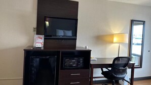 A hotel room with a desk, a chair, a television, and a refrigerator. - Red Roof Inn Fredericksburg South (Fredericksburg)