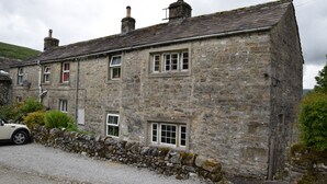 A stone building with multiple windows and a stone wall. - Sweetbriar Cottage B&B and Camping (Skipton)
