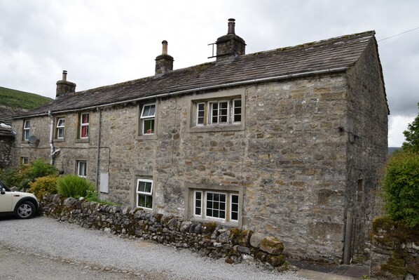 A stone building with multiple windows and a stone wall. - Sweetbriar Cottage B&B and Camping (Skipton)