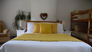 A bedroom with a bed, a nightstand, a lamp, a chair, a plant, and a bunk bed. - Sweetbriar Cottage B&B and Camping (Skipton)