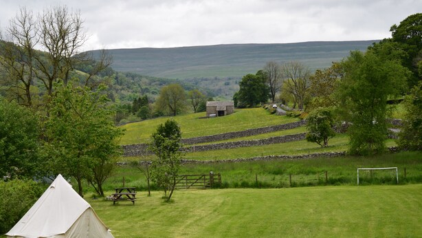 A grassy field with a tent, stone walls, and a small building in the distance. - Sweetbriar Cottage B&B and Camping (Skipton)