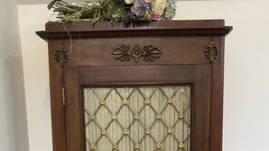 A dark wooden cabinet with a glass door featuring a diamond pattern and brass accents.