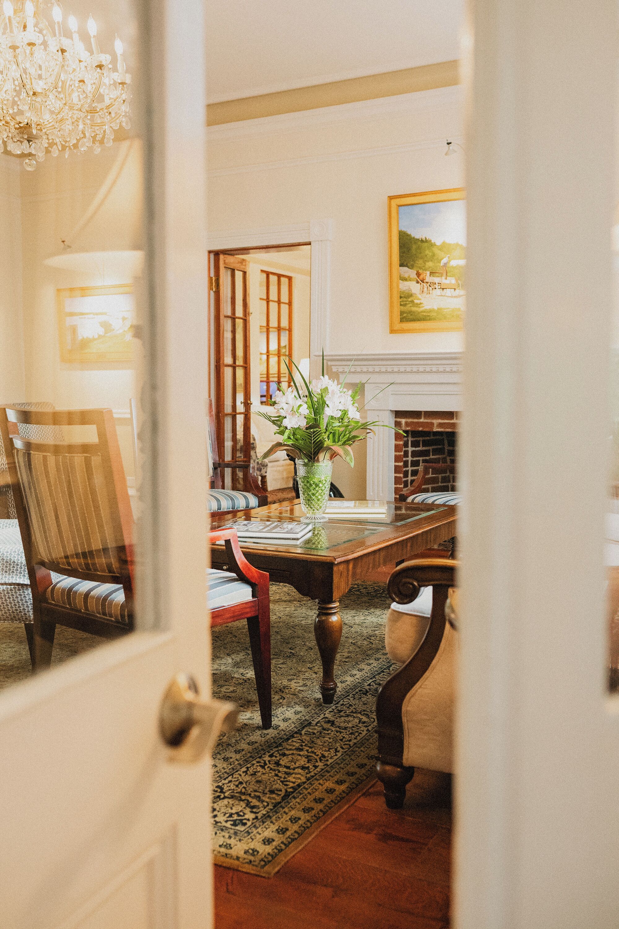 Une salle à manger traditionnelle avec une table en bois, des chaises, un vase de fleurs, une cheminée et un tableau au mur.