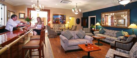 A spacious living area with a bar, seating arrangements, and a large mirror.