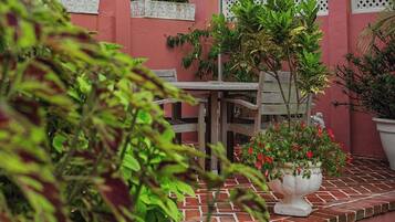 Un patio con una mesa, sillas, un paraguas blanco y plantas en macetas.