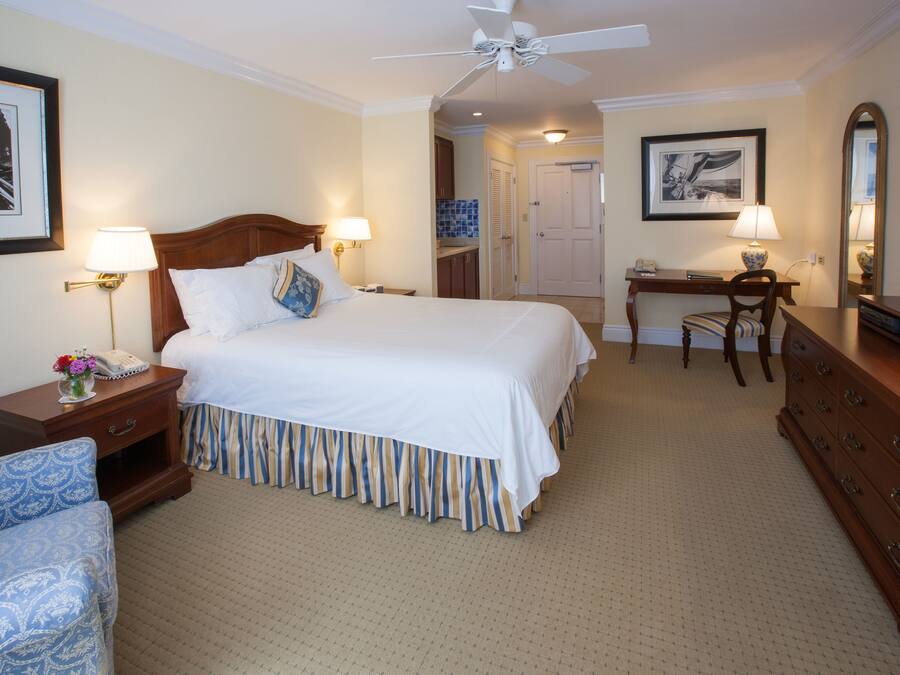 A hotel room with a large bed, bedside lamps, a desk, a chair, and a dresser.