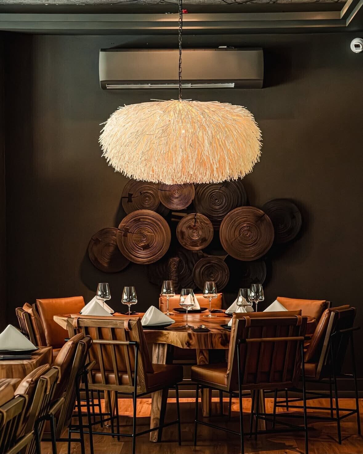 Un comedor con una mesa redonda, sillas de cuero y una lámpara colgante.