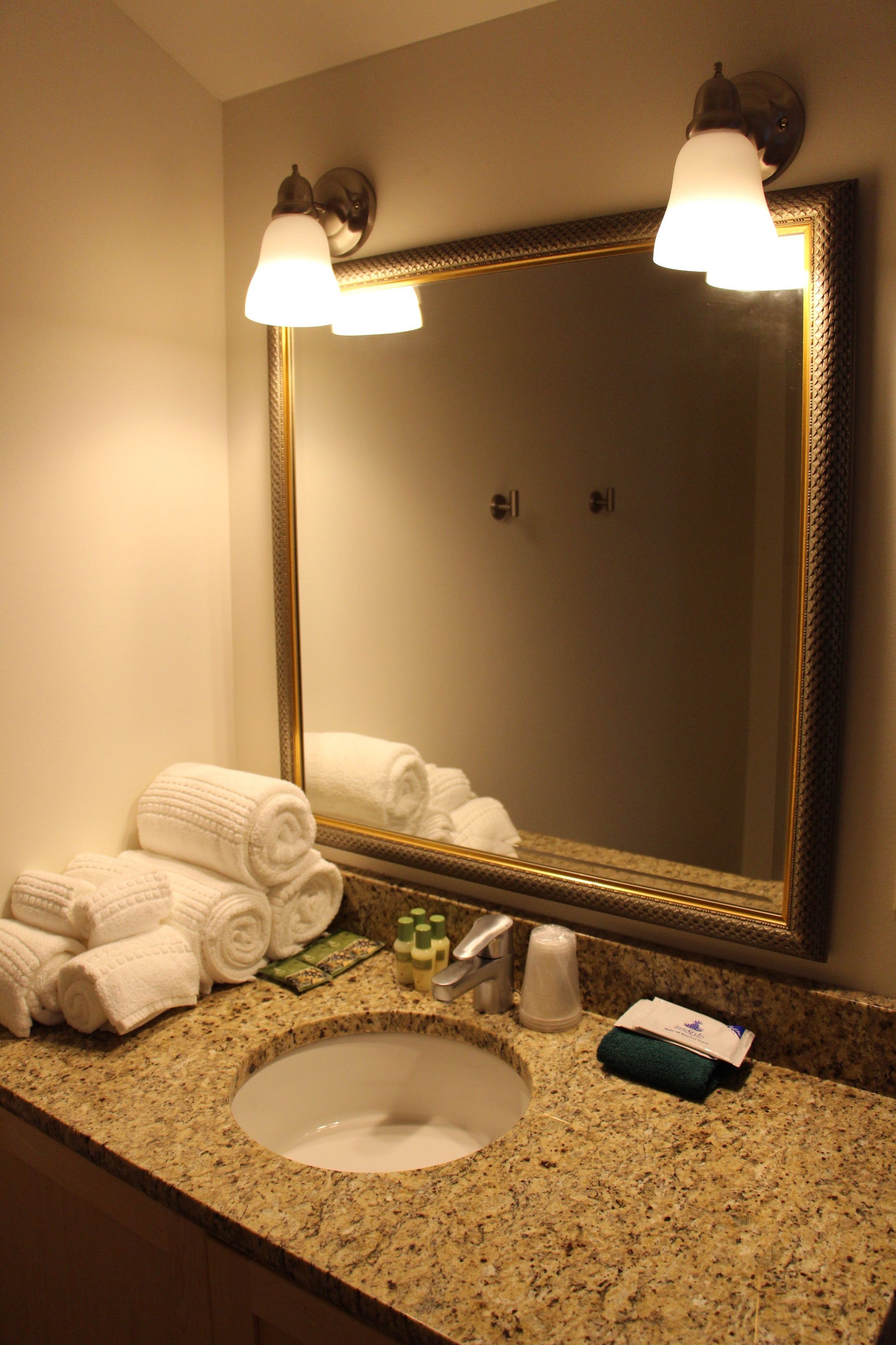 A bathroom with a sink, mirror, and towels.