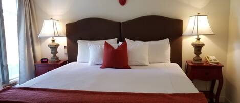 A hotel room with a large bed, two bedside tables with lamps, a wall-mounted telephone, and a decorative antelope head.