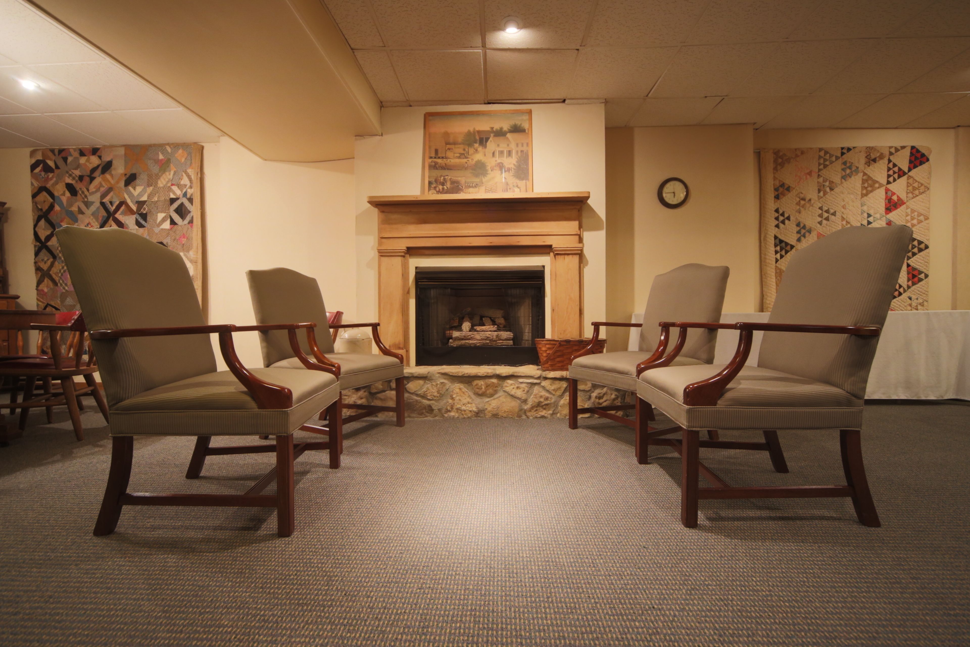 A room with a fireplace, two armchairs, a table, and patterned walls.