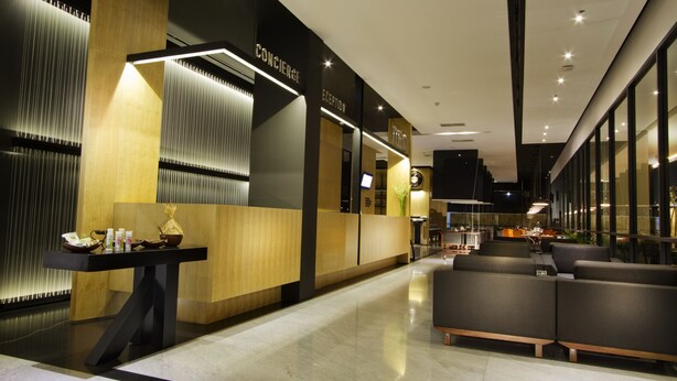 Un hall d’hôtel moderne doté d’un comptoir d’accueil, d’un espace salon et offrant une vue sur l’intérieur.