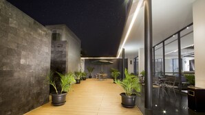 Un espace extérieur moderne doté d’un plancher en bois, de plantes en pot et d’un aménagement avec des sièges.