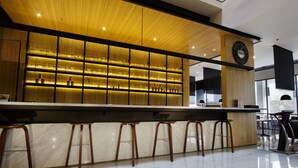 Un espace bar moderne avec un plafond en bois, un comptoir en marbre et des tabourets de bar.
